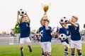 Happy boys in elementary school sports team celebrating soccer success in tournament final game Royalty Free Stock Photo