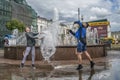 Happy boys and girls are pouring water each other near fountain. Children have fun during `Wet monday` ukrainian Easter tradition