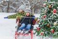 Happy boys sledding near christmas tree in winter day outdoor