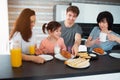Happy breakfast of a large family in the kitchen. Siblings, parents and children, mother and grandmother. Father and Royalty Free Stock Photo