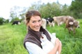 Happy breeder holding fresh milk, cows in the back