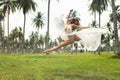 Beautiful bride is jumping in dance on the field with a lot of palm trees Royalty Free Stock Photo