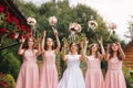 Happy bride with bridesmaid hold bouquets and have fun outside. Beautiful bridesmaid in same dresses stand by the Royalty Free Stock Photo