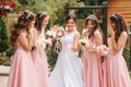 Happy bride with bridesmaid hold bouquets and have fun outside. Beautiful bridesmaid in same dresses stand by the Royalty Free Stock Photo