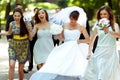 Happy bride and bridesmaids walk along the path in the park