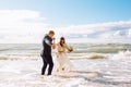 Happy bride and groom on the beach sea having fun. Newlyweds couple jump into sea water waves at sunny summer day. Just Royalty Free Stock Photo