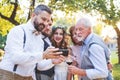 Bride, groom and guests with smartphones taking selfie outside at wedding reception. Royalty Free Stock Photo