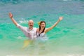 Happy bride and groom having fun in the waves on a tropical beach. Wedding and honeymoon on the tropical island. Royalty Free Stock Photo