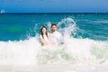 Happy bride and groom having fun in the waves on a tropical beach Royalty Free Stock Photo