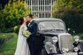 stylish bride and groom sensually posing near retro car with boh Royalty Free Stock Photo