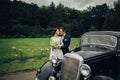 stylish bride and groom sensually posing near retro car with boh Royalty Free Stock Photo