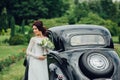 stylish bride and groom sensually posing near retro car with boh Royalty Free Stock Photo