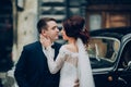 stylish bride and groom sensually posing near retro car with boh Royalty Free Stock Photo