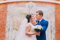 Happy bride and groom kissing on background of beautifully decorated red brick wall Royalty Free Stock Photo