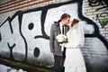 Happy bride and groom kissing near graffiti