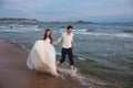 Happy bride and groom run along ocean shore. Newlyweds having fun at wedding day on tropical beach Royalty Free Stock Photo