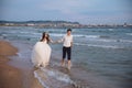 Happy bride and groom run along ocean shore. Newlyweds having fun at wedding day on tropical beach Royalty Free Stock Photo