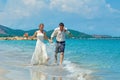 Happy Bride and groom running on a beautiful tropical beach Royalty Free Stock Photo
