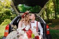 Happy bride and groom sitting in the trunk of a car Royalty Free Stock Photo