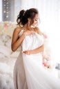 Happy bride is holding her wedding dress in the boudoir room.