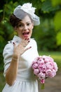 Happy bride laughing, covering mouth with her hand with bouquet of peony flowers.