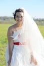 Happy bride outdoor portrait in white dress, looking at camera, on green field Royalty Free Stock Photo