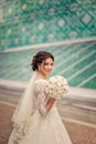 Happy bride with unusual bouquet on the background of modern glass building