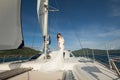 Happy bride on a yacht. White yacht with sail set goes along the island.