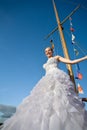 Happy brideposing at yacht mast agaisnt blue sky