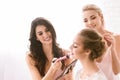 Happy bridesmaids helping the bride to get ready