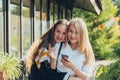 Happy bright positive moments of two stylish girls hugging and looking at the phone, discussing something on the street in the Royalty Free Stock Photo