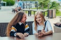 Happy bright positive moments of two stylish girls hugging and looking at the phone, discussing something on the street in the Royalty Free Stock Photo