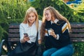 Happy bright positive moments of two stylish girls hugging and looking at the phone, discussing something on the street in the Royalty Free Stock Photo