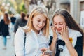 Happy bright positive moments of two stylish girls hugging and looking at the phone, discussing something on the street in the Royalty Free Stock Photo