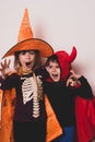 Happy brother and sister at Halloween party. People are having fun indoors. Children in costumes of skeletons and witches. Royalty Free Stock Photo