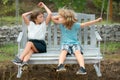 Happy brother and sister playing in summer park outdoors. Little boy and girl kids enjoying summer. Kids swinging at Royalty Free Stock Photo