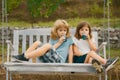 Happy brother and sister swinging on swing in summer park outdoors. Little boy and girl kids drink green smoothie Royalty Free Stock Photo