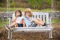 Happy brother and sister swinging on swing in summer park outdoors. Little boy and girl kids drink green smoothie Royalty Free Stock Photo