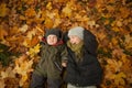 Happy brothers laughing and lying on autum fall leaves background. Boy 9 years old and little baby boy 6 months old smiling Royalty Free Stock Photo