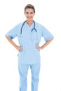 Happy brown haired nurse in blue scrubs posing with hands on the hips Royalty Free Stock Photo