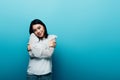Brunette asian woman hugging herself on blue background Royalty Free Stock Photo