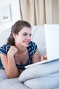 Happy brunette on couch using her laptop Royalty Free Stock Photo