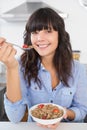 Happy brunette eating bowl of cereal and fruit