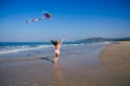 Happy brunette girl in a bathing suit and short pink playing with flying kite on tropical beach copyspase Royalty Free Stock Photo