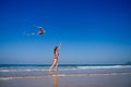 Happy brunette girl in a bathing suit and short pink playing with flying kite on tropical beach copyspase hills and Royalty Free Stock Photo