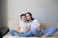 A happy brunette mom in a white T-shirt and jeans hugs her loving son sitting at home on the couch Royalty Free Stock Photo