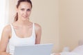 Happy brunette sitting on bed using her laptop Royalty Free Stock Photo