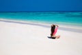 Happy brunette woman enjoying on exotic beach in summer by tropical blue water. Attractive girl with long hair sunbathing and res Royalty Free Stock Photo