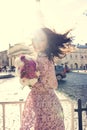 Happy brunette woman with fluttering hair in wind wearing fashionable dress