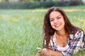 Happy brunette woman lying on grass in park with smartphone Royalty Free Stock Photo